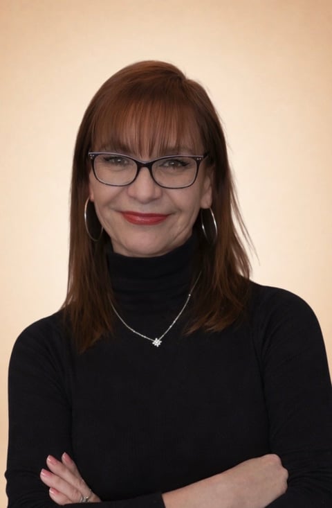 Woman with long brown hair, glasses, and red lipstick wearing a black turtleneck against a beige background